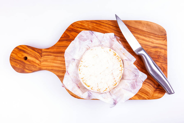Brie cheese on an olive wood cutting board, flat lay - Фото, изображение