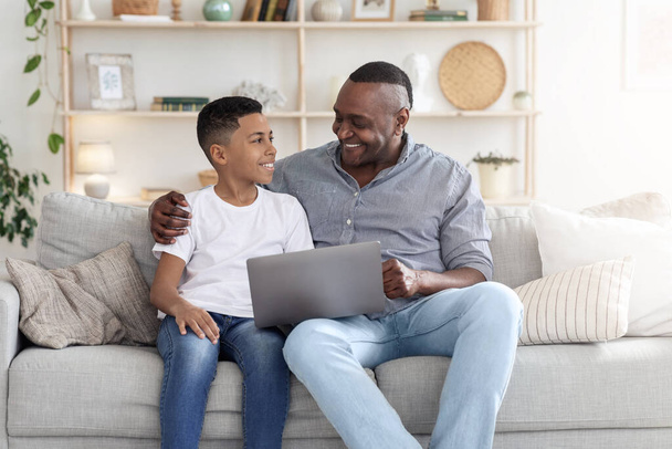 zwart peuter jongen onderwijzen zijn grootvader hoe naar gebruik laptop - Foto, afbeelding