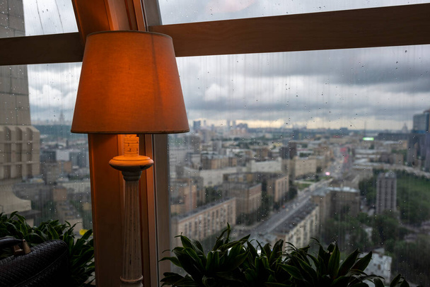 una vista de una gran ciudad a través de la ventana donde se puede ver que llueve afuera
 - Foto, Imagen