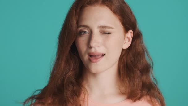 Close up krásný ryšavý dívka sebevědomě mrkání na kameru přes barevné pozadí - Záběry, video