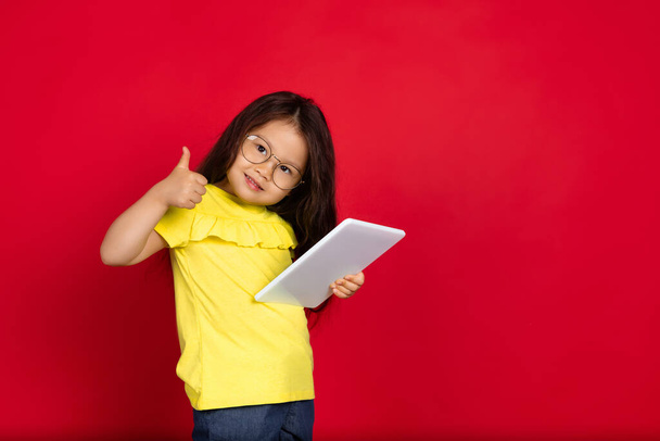 Beautiful emotional little girl isolated on red background. Half-lenght portrait of happy child gesturing - Foto, imagen