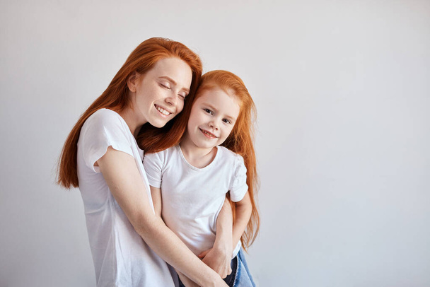 Beautiful young red haired mother hugging her cute little baby. - 写真・画像