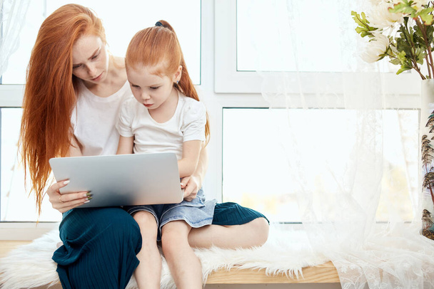 Мать и дочь используют ноутбук дома - Фото, изображение