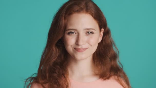 Close up attractive redhead girl slyly looking in camera over colorful background. Tricky expression - Footage, Video