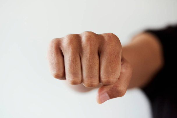 closeup of the fist of a young caucasian man throwing a punch to the observer or fist bumping, on a white background - Photo, Image