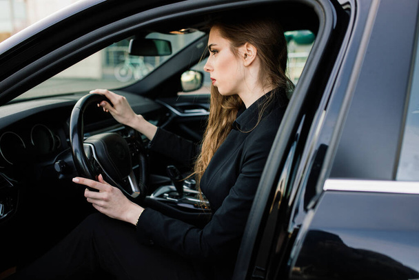 Junge Geschäftsfrau in schwarzer Kleidung mit teurem Auto - Foto, Bild