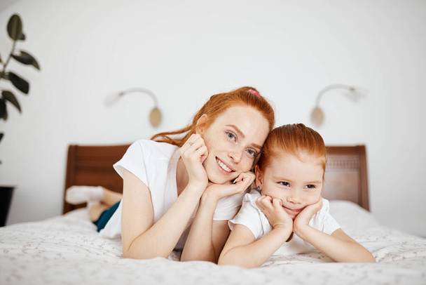 Mother and daughter enjoy in bed at home and looking at the camera. - Foto, immagini