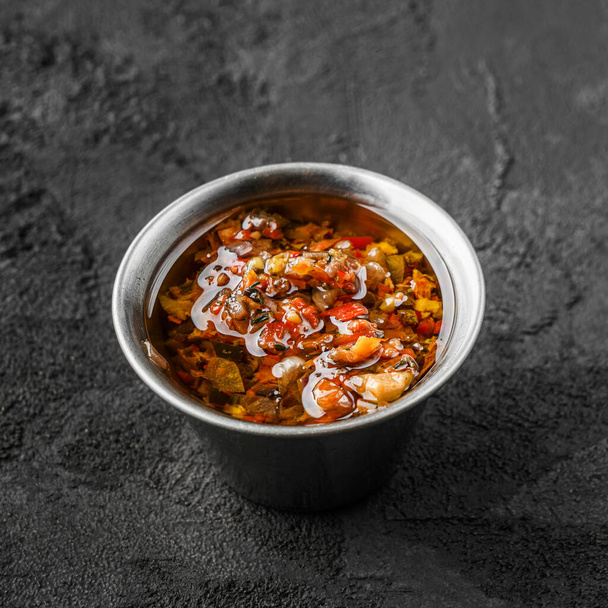 Sauce mit Paprika in Schüssel auf schwarzem Stein Hintergrund - Foto, Bild