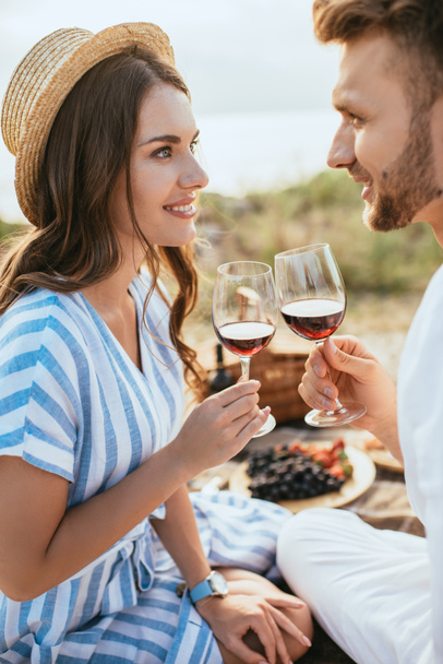 cheerful couple clinking glasses with red wine outside  - Fotografie, Obrázek