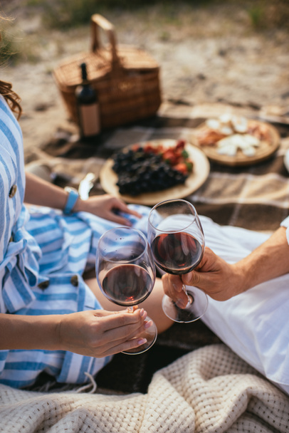 cropped view of couple clinking glasses with red wine  - Photo, Image