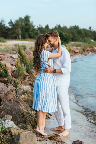 handsome man and happy woman hugging near lake  - Photo, Image