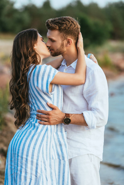 handsome man and beautiful woman with closed eyes kissing outside - Photo, Image