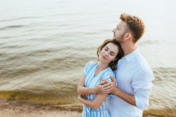 bearded man hugging beautiful girlfriend near river - Photo, image