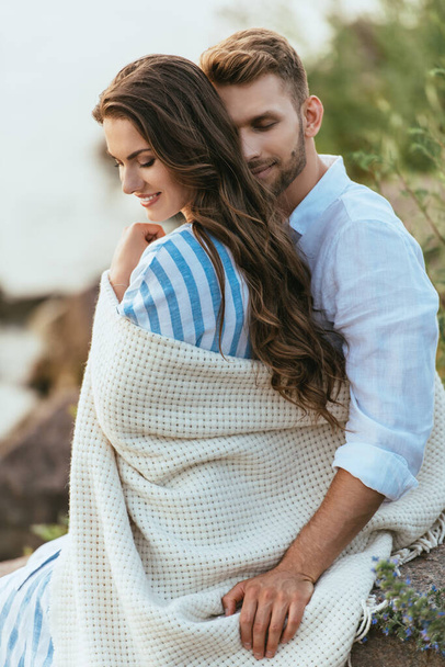 бородатый мужчина трогает одеяло, обнимая девушку снаружи - Фото, изображение