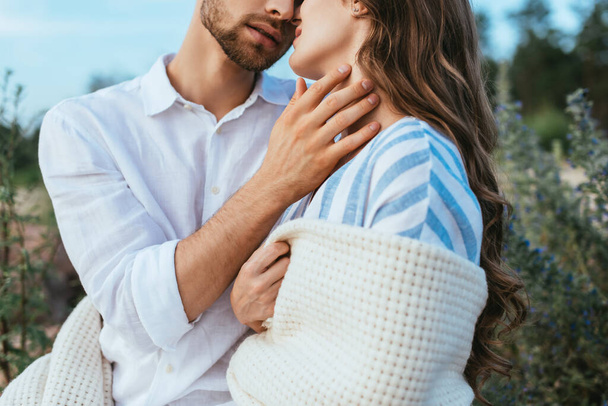cropped view of bearded man touching girlfriend wrapped in blanket  - Foto, Imagen