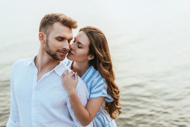attraente donna abbracciare bello uomo con gli occhi chiusi vicino al fiume  - Foto, immagini