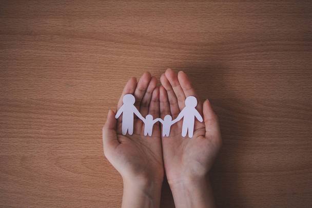 hands holding paper family cutout, family home. - Фото, зображення