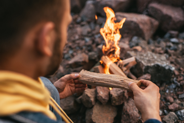 selective focus of man putting log in burning bonfire  - Фото, зображення