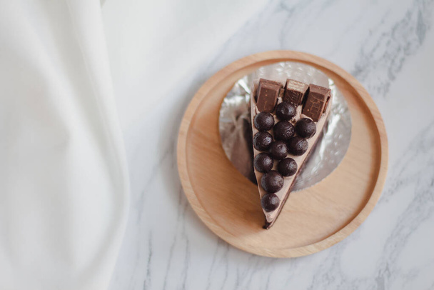Rebanada de pastel de chocolate con bola de chocolate sobre fondo de mármol blanco.
. - Foto, Imagen