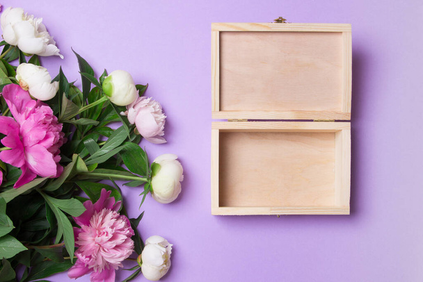 ピンクと白の牡丹の花束と紫色の紙の背景に空のオープン木製の箱. - 写真・画像