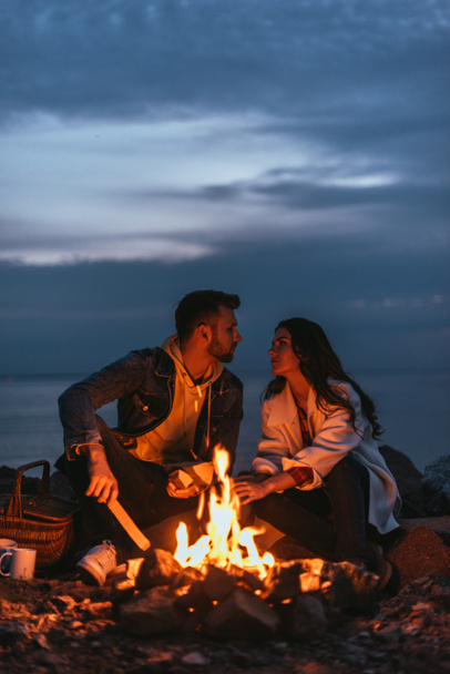 selective focus of couple looking at each other near bonfire  - Photo, Image