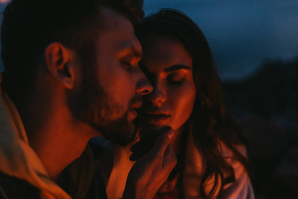 selectieve focus van bebaarde man aanraken aantrekkelijke vrouw 's nachts - Foto, afbeelding