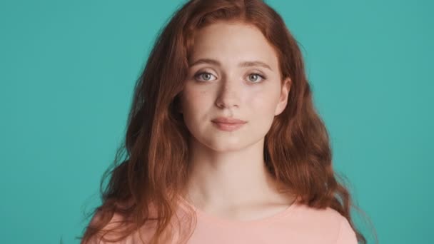 Muotokuva kaunis punapää tyttö luottavaisesti katsot kameran yli värikäs tausta - Materiaali, video