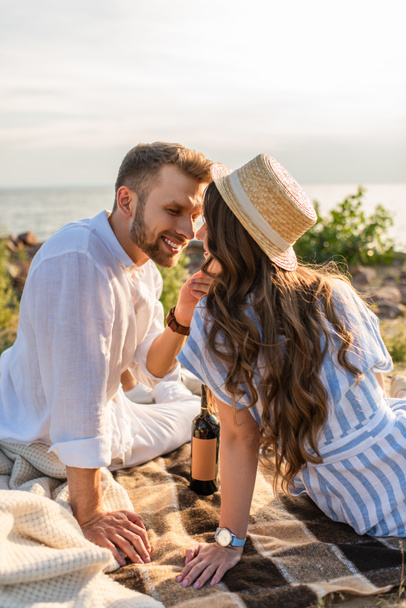 boldog férfi megható arc vidám nő szalmakalapban közel üveg bor - Fotó, kép