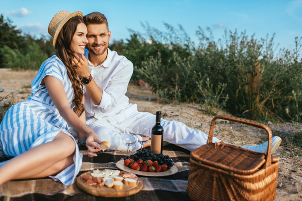 onnellinen pari istuu lähellä maukasta ruokaa ja pullo viiniä  - Valokuva, kuva
