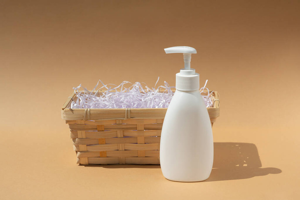 wicker basket and white dispenser bottle, for spa cosmetic products on a beige background - Foto, immagini