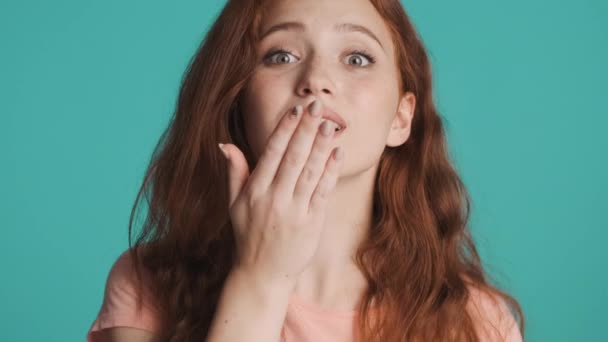 Krásná okouzlující zrzka dívka šťastně posílá vzdušný polibek na kameru přes barevné pozadí. Flirtovaný výraz - Záběry, video