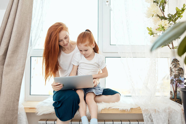 Mother and daughter using laptop computer at home - Φωτογραφία, εικόνα