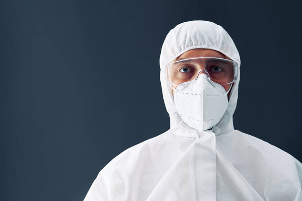 Doctor in protective medical suit with copy space on black background - Фото, зображення
