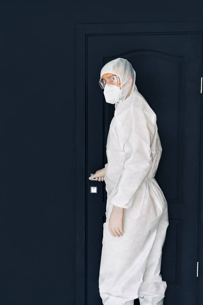 Doctor in protective medical suit open black door - Фото, зображення