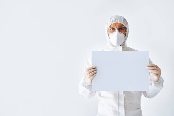 Médico en traje médico protector mostrando pancarta en blanco con espacio de copia para texto
 - Foto, Imagen