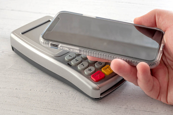 Yhteystiedot maksu, digitaalinen lompakko ja NFC teknologian käsitteellinen idea älypuhelimen tehdä liiketoimen luottokorttipäätteen eristetty valkoisella puulla tausta - Valokuva, kuva