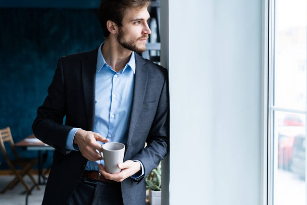 Happy attracive young businessman drinking coffee in office. - Foto, Imagen