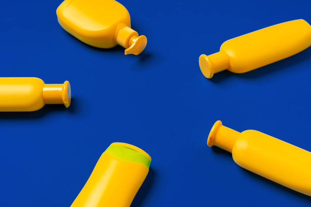 Bright yellow bottles of sunscreen product on dark blue paper background - Fotografie, Obrázek