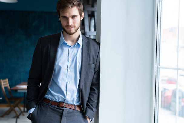 Confident professional handsome businessman standing near window in his office - Fotoğraf, Görsel