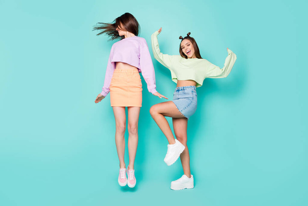Full length body size of two nice attractive slim fit girlish cheerful cheery girls having fun jumping dancing fooling isolated over bright vivid shine vibrant blue green turquoise color background - Photo, Image