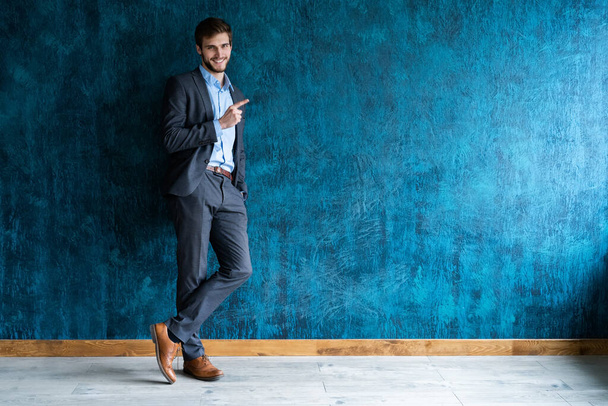 Full length portrait of young handsome businessman with smile pointing with finger. - Foto, afbeelding