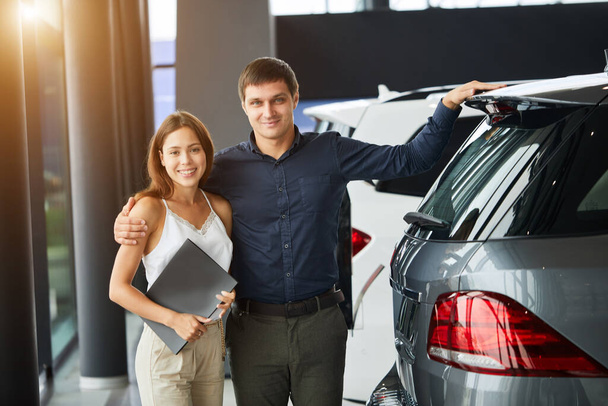 Loving smart couple choosing a car at the car dealership showroom - Zdjęcie, obraz