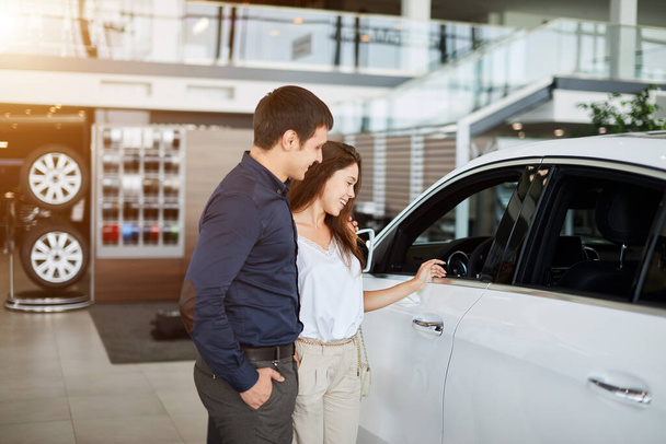 Young couple in elegant summer time clothes choose a new car at car dealership - Foto, Imagem