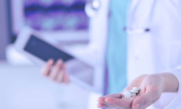 Close-up shot of doctors hands holding pills and tablet at clinic. - Fotó, kép