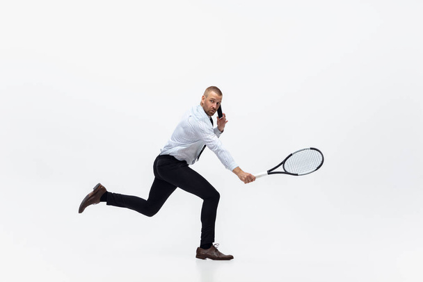 Time for movement. Man in office clothes plays tennis isolated on white studio background. - Fotoğraf, Görsel