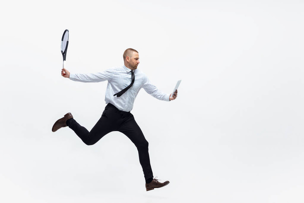Time for movement. Man in office clothes plays tennis isolated on white studio background. - Foto, Imagem