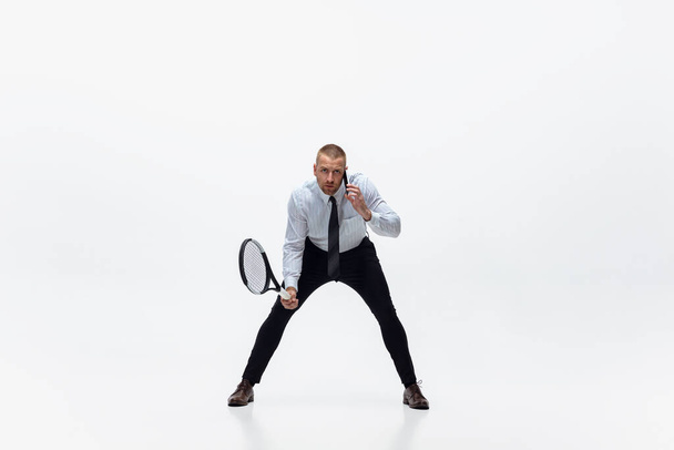 Time for movement. Man in office clothes plays tennis isolated on white studio background. - Photo, image