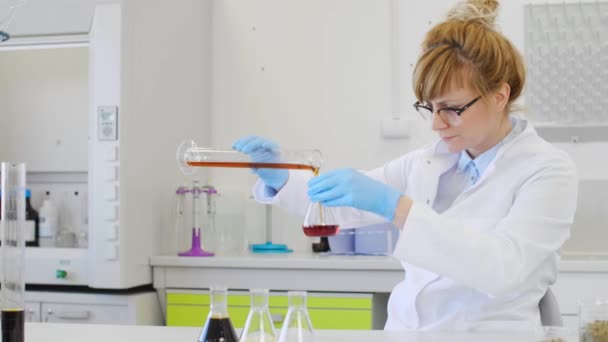 Close up of chemical scientists working with hemp CBD and CBDa oil in laboratory. She is using erlenmeyer flasks. Cannabis pharmaceutical healthcare concept. - Footage, Video