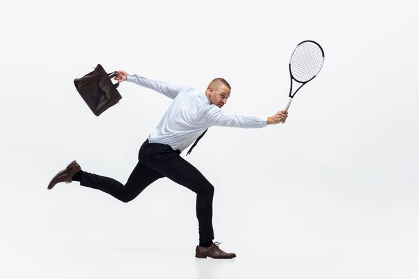Time for movement. Man in office clothes plays tennis isolated on white studio background. - Fotoğraf, Görsel