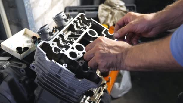 Widok na ręce profesjonalnego mechanika naprawy zdemontowany silnik. Naprawiacz pracujący w warsztacie lub warsztacie. Zajmował się serwisem samochodów. Powolny ruch Zamknij - Materiał filmowy, wideo